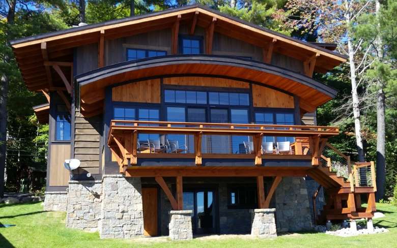 exterior of a wooden home with large windows and a deck