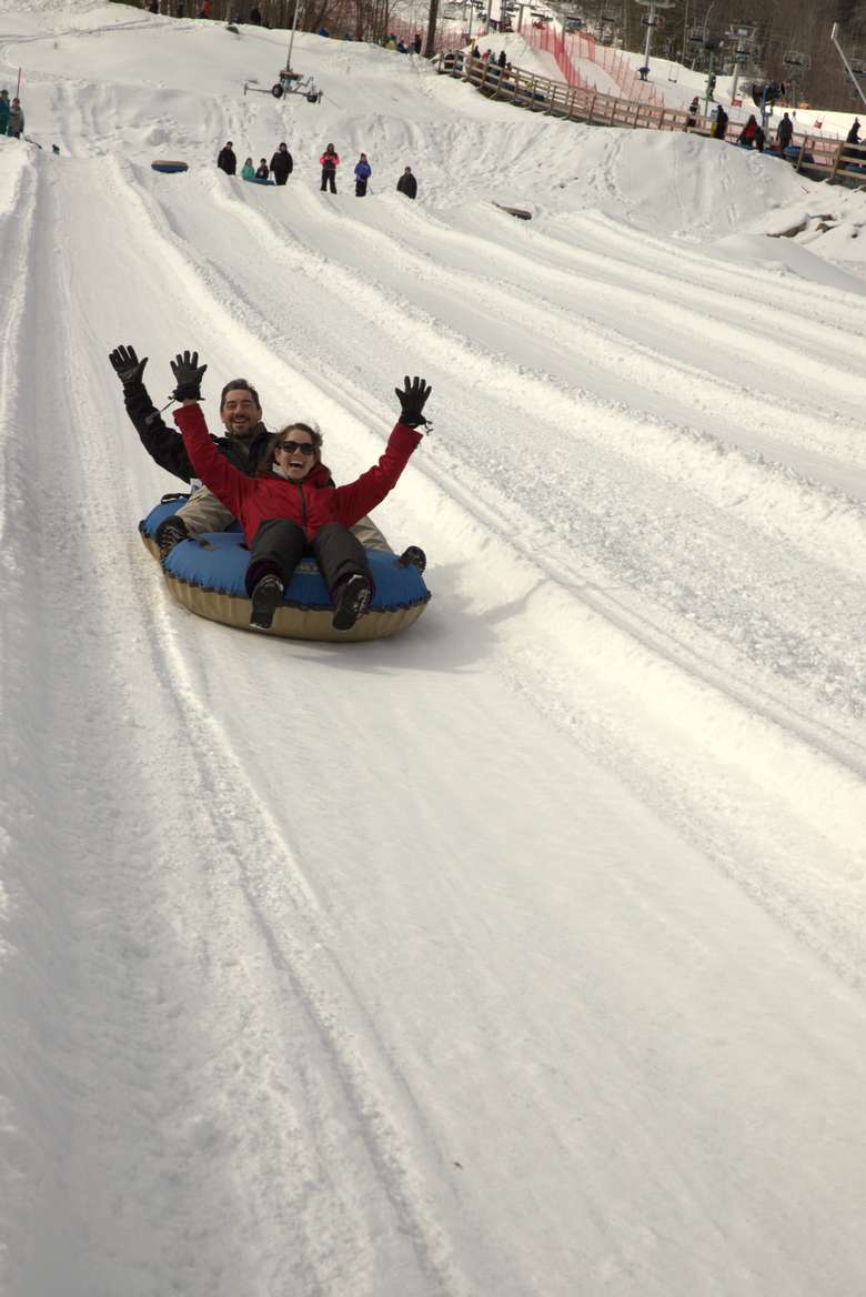 two people tubing down a snowy hill