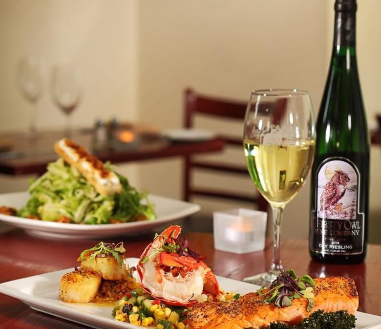 restaurant table with wine bottle, wine glass, and plates of food