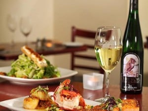 restaurant table with wine bottle, wine glass, and plates of food