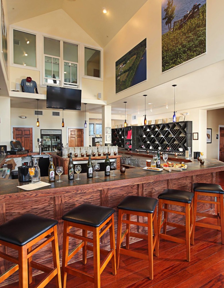 a wine bar with seating around it, and wine bottles and plates on the counter
