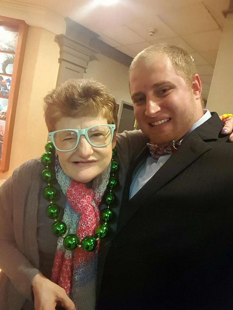 Two people dressed up, including a woman wearing teal glasses