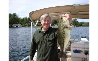 Man holding a large bass on a boat in Lake George