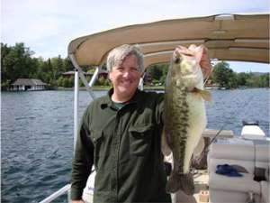 Man holding a large bass on a boat in Lake George