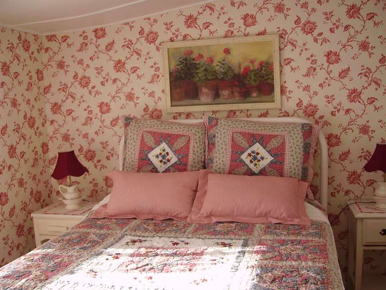 a bedroom with pink floral designs on the walls and blankets