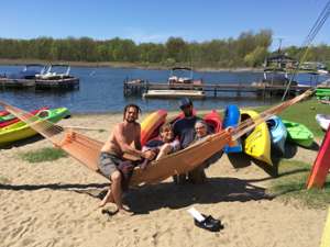 four people posing in a hammock with colorful kayaks in the background