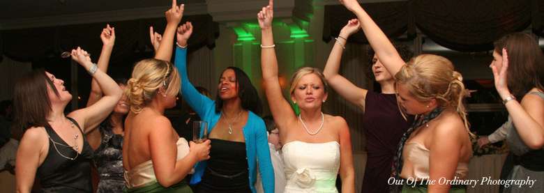 a group of women at a wedding dancing with their arms up