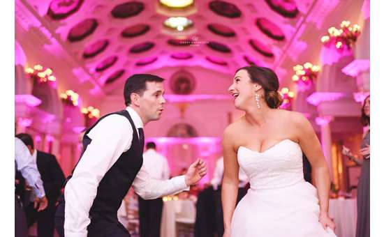 bride and groom dancing, there's pink up lighting on the walls