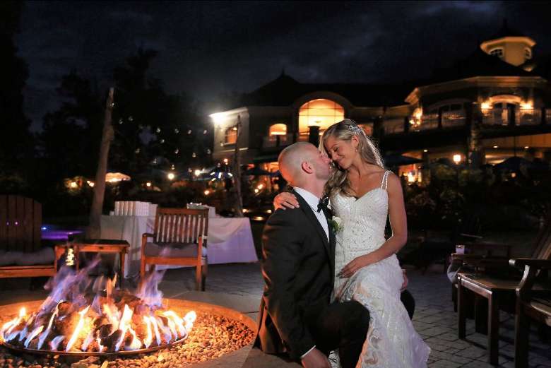 bride and groom looking lovingly at each other by a fire pit
