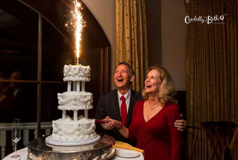 bride and groom looking at a sparkler shooting flames out of a cake
