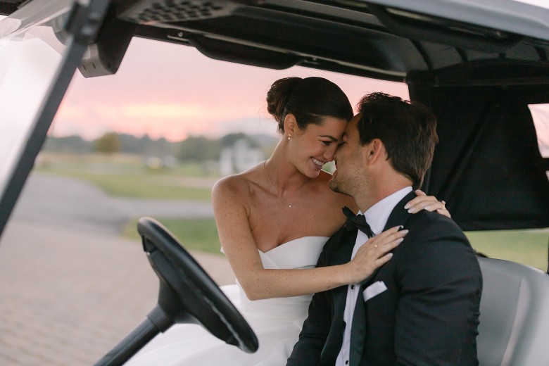 a bride and groom inside a golf cart at sunset