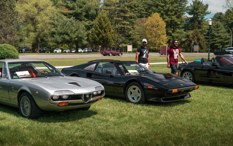 two men walking by classic sports cars on display