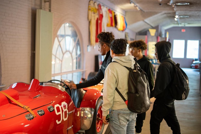 a group of four checking out a classic red automobile in a museum