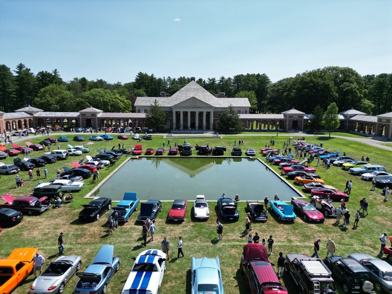 a drone shot of a car show in a large park area