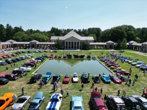 a drone shot of a car show in a large park area
