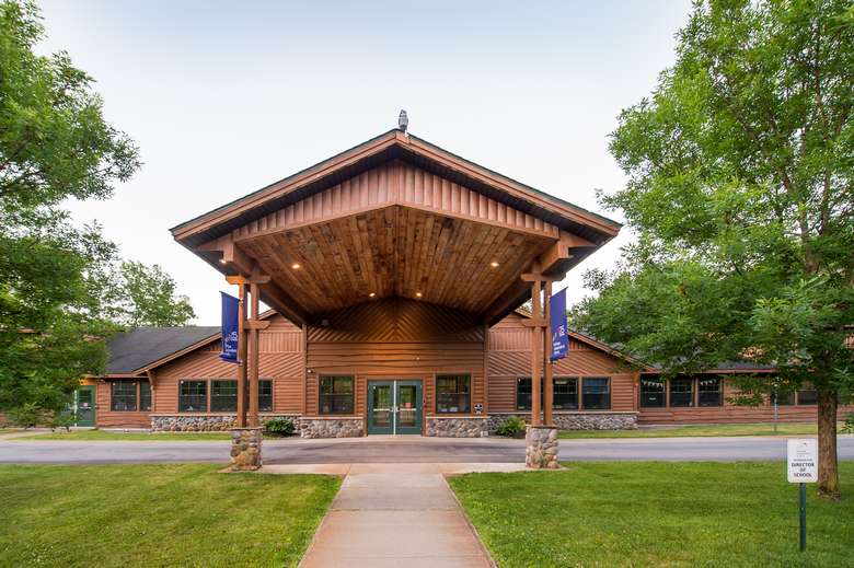 front entrance of saratoga independent school, a log building with a large front overhang covering the driveway