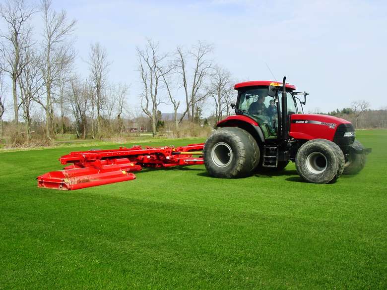 a red tractor mowing a large lawn