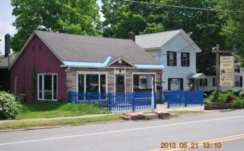 small building that's red on one side and has stone on the front with a bright blue fence in the front
