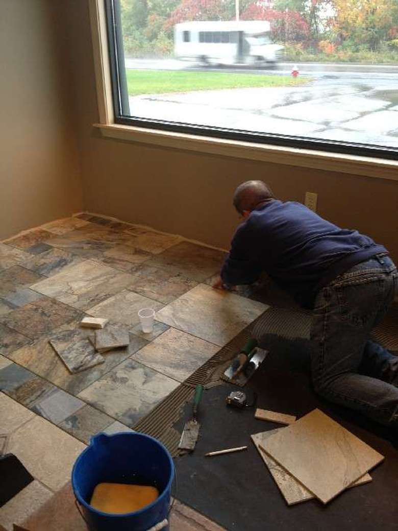 man laying tile in a home