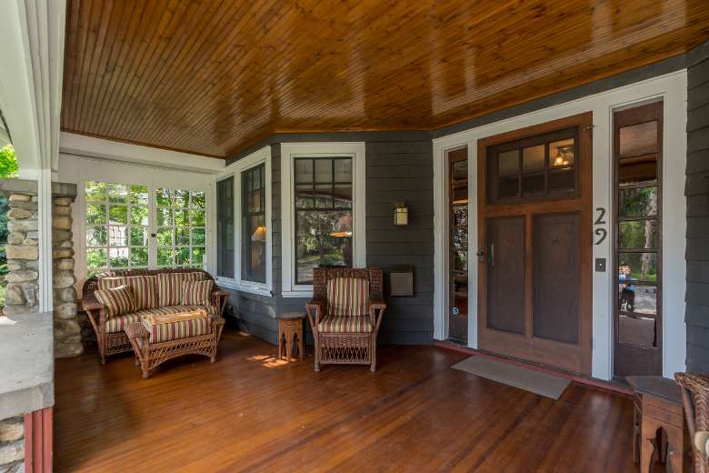 covered front porch with wood floor and ceiling and stone pillar