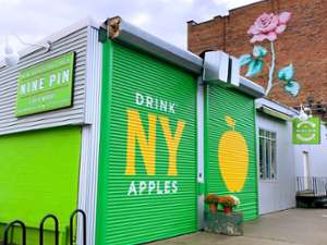 Nine Pin Cider's front garage doors that read "Drink NY Apples" with an image of an apple on second door