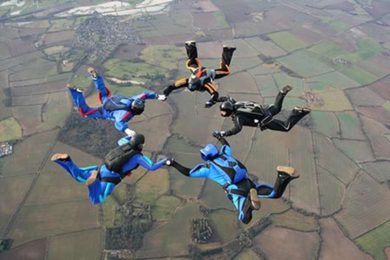 Five skydivers holding hands in a circle