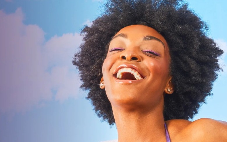 a woman smiling in front of cloud and blue sky background