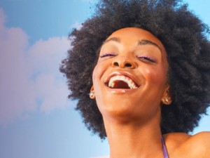 a woman smiling in front of cloud and blue sky background