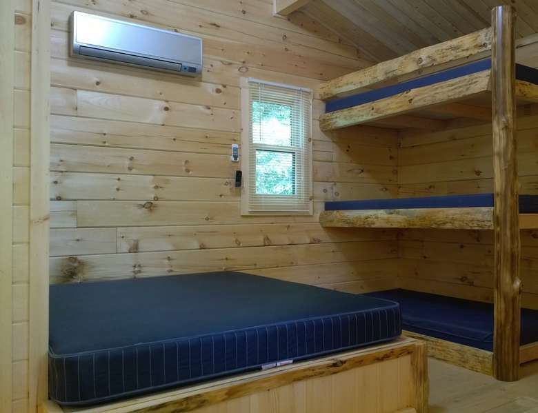 a blue mattress and three bunk beds in one room inside rustic wooden cabin