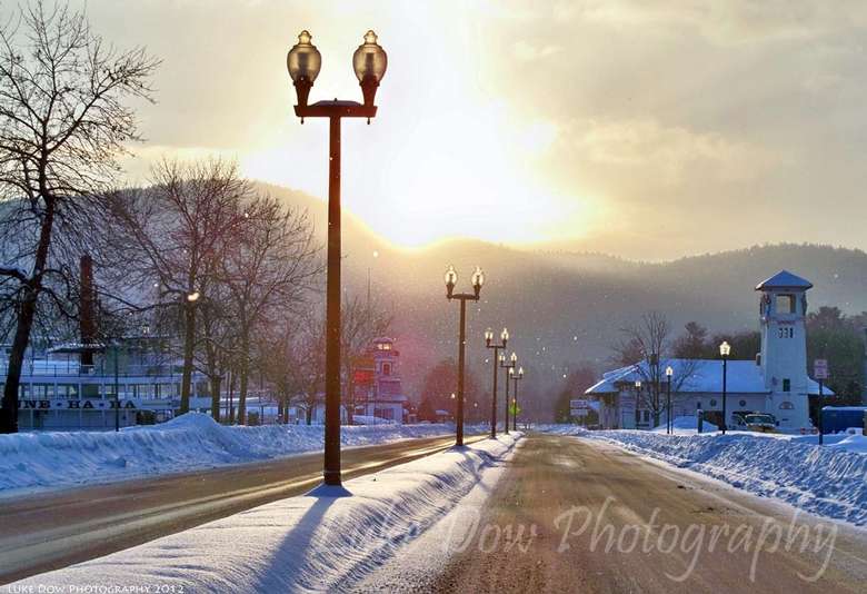 lamp posts along a road during winter, sun is shining in the sky