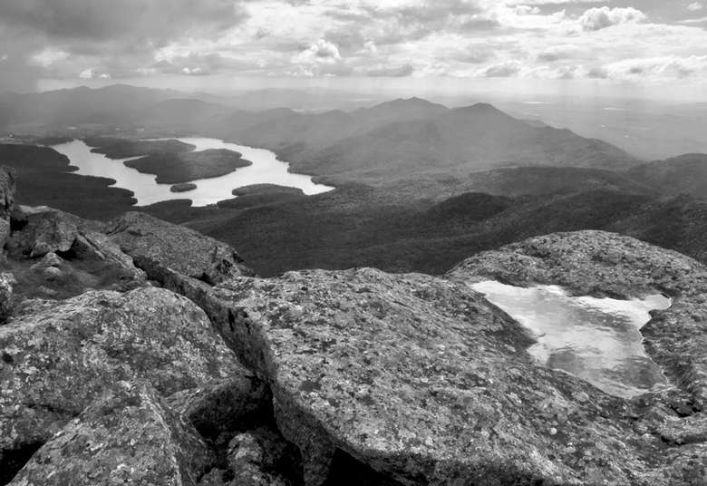a black and white photograph of a mountain landscape from the summit of a peak