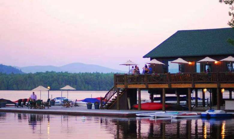 outdoor deck and patio area of a lakeside restaurant with boats at the dock