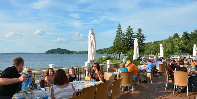 an expansive deck by the lake with people dining
