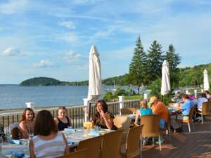 an expansive deck by the lake with people dining