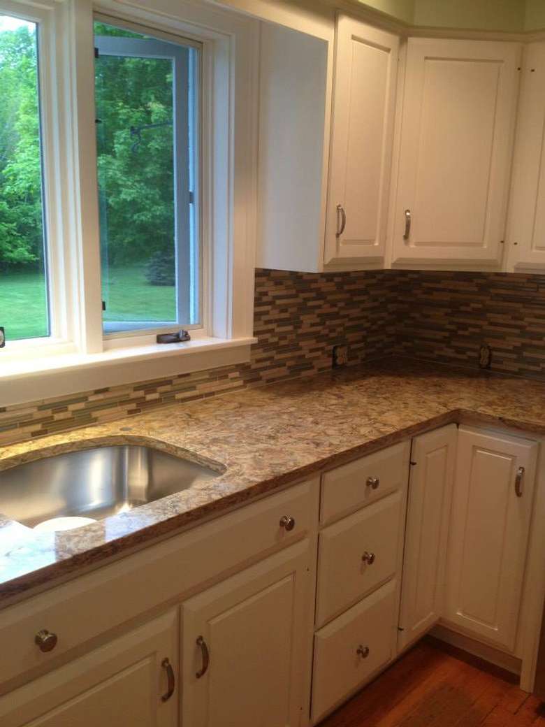 a kitchen with a sink, cabinet countertops, and a window