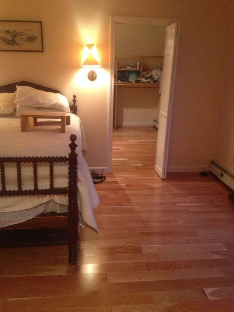 a bedroom with wooden floors and a bed with white covers