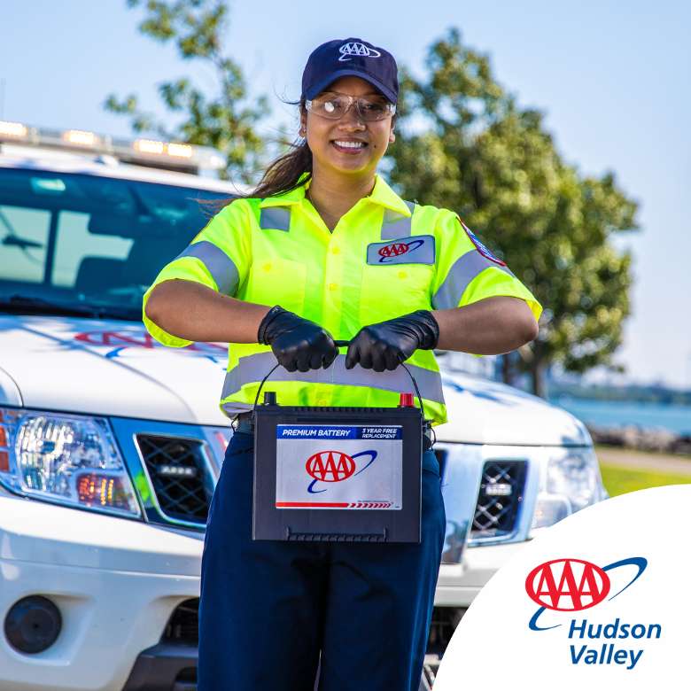 Image of female Triple A fleet driver holding up a Triple A vehicle battery in front of her service truck.