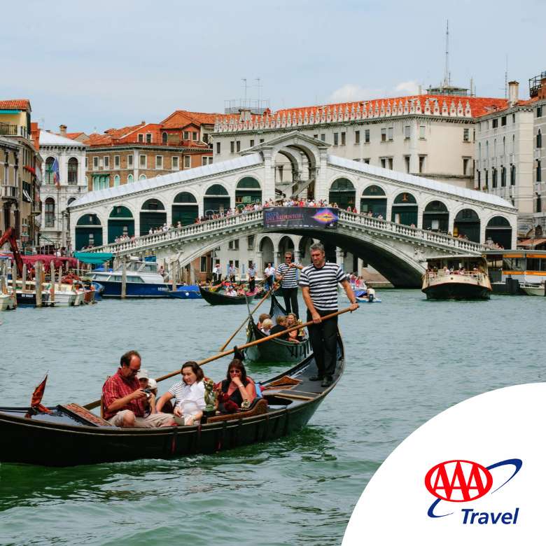 Image of a group of people on a Gondola Ride in Venice, Italy, with beautiful architecture in the background.