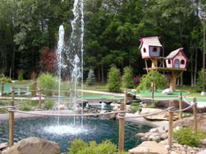 mini-golf course with a water feature in the middle and whimsical looking treehouses in the background