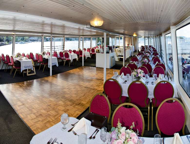 tables on a boat set up for a wedding reception with a dance floor in the middle