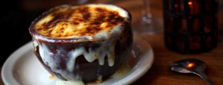 crock of french onion soup with melted cheese browned on top and running down the sides