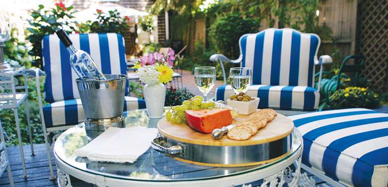 blue and white striped patio furniture surrounding a table with a charcuterie board and a bottle of wine on it