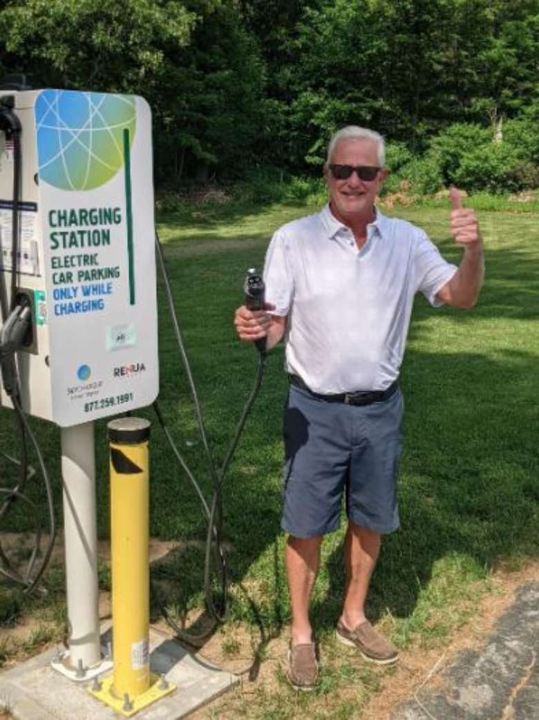 man standing next to an electric vehicle charging station