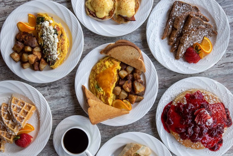 spread of different breakfast foods on plates