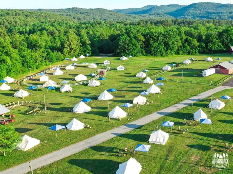 aerial view of glamping sites on a flat property near woods
