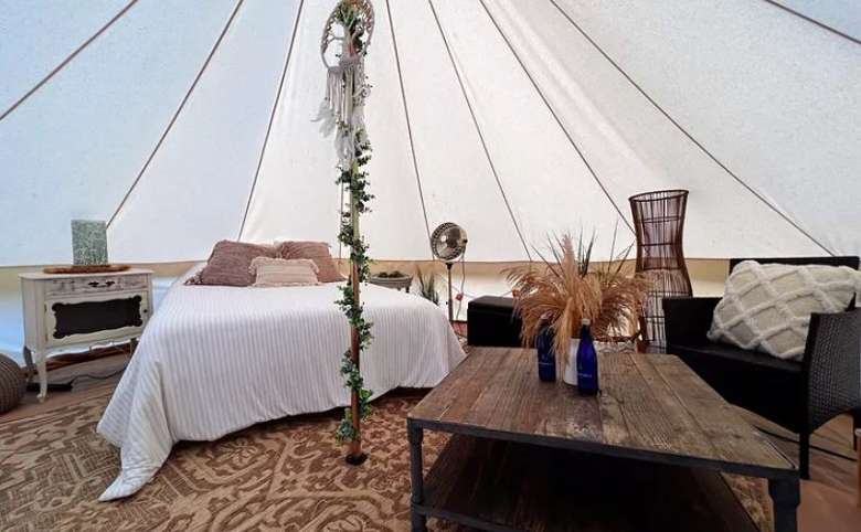 a bed and rustic, elegant decor such as a table and chair in a glamping tent