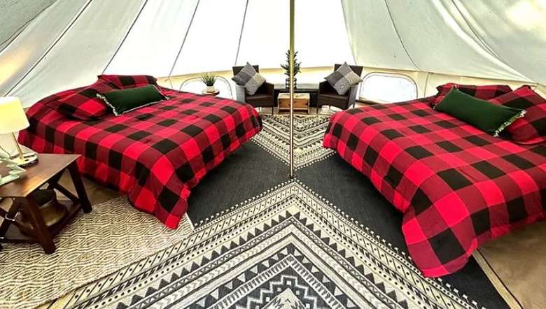 two beds with black and red covers in a glamping tent