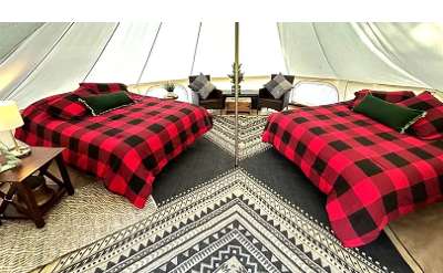 two beds with black and red covers in a glamping tent