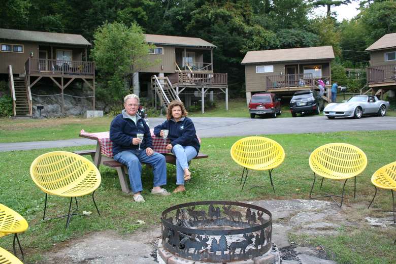 a couple sitting in chairs around a spot for a bonfire