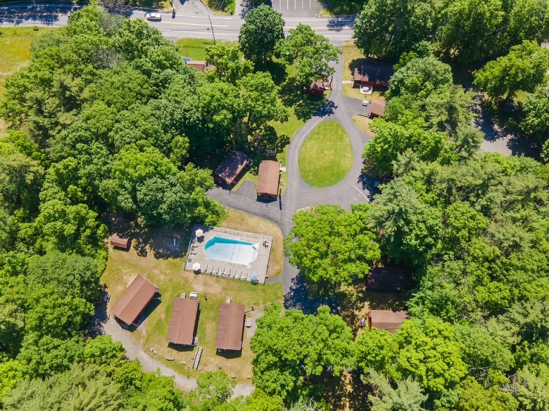 aerial view of a wooded lodging property with a pool